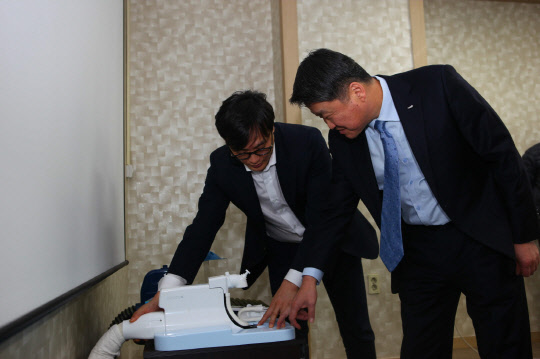 김학도 한국산업기술진흥원 원장(오른쪽)이 지난 15일 경기도 성남에 있는 큐라코에 방문해 관련 제품에 대한 설명을 듣고 있다.    한국산업기술진흥원 제공